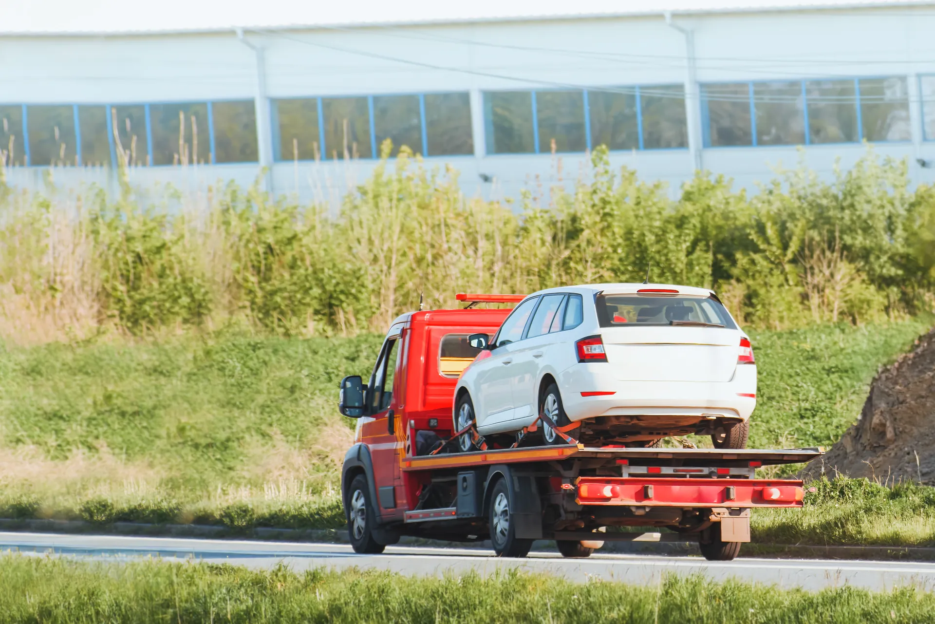 Evakuators ar vieglo automašīnu uz platformas brauc pa ceļu