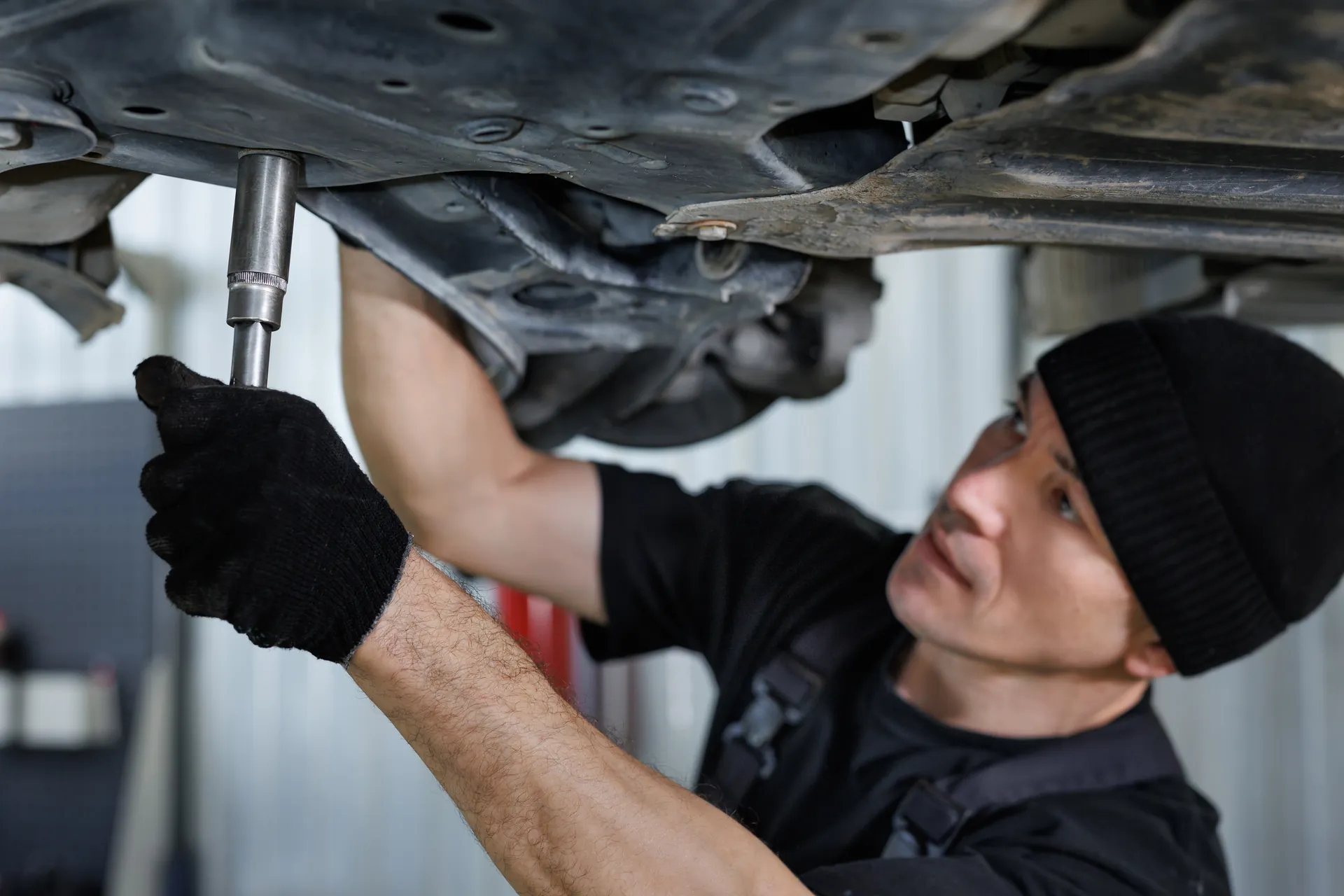 Meistars zem auto uz pacēlāja pārbauda stūres reiku